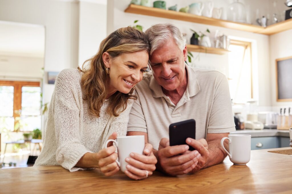 Senior couple on smartphone reading online social media post, search holiday house website or retir